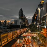 Cityscape at twilight showing busy traffic, skyscrapers, and an elevated train line in an urban setting. — 2024 Aetna Medicar