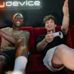Two friends having fun and playing video games on a couch indoors. — Betting Beyond Borders: UFABET's Prospective Success in