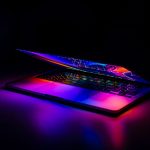 A partially closed MacBook with vibrant, colorful light reflections on a dark background. — Breaking Data From the World of A
