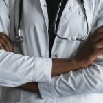Close-up of a confident doctor in a lab coat standing with crossed arms and stethoscope. — Expert Minimally Invasive Spine Su