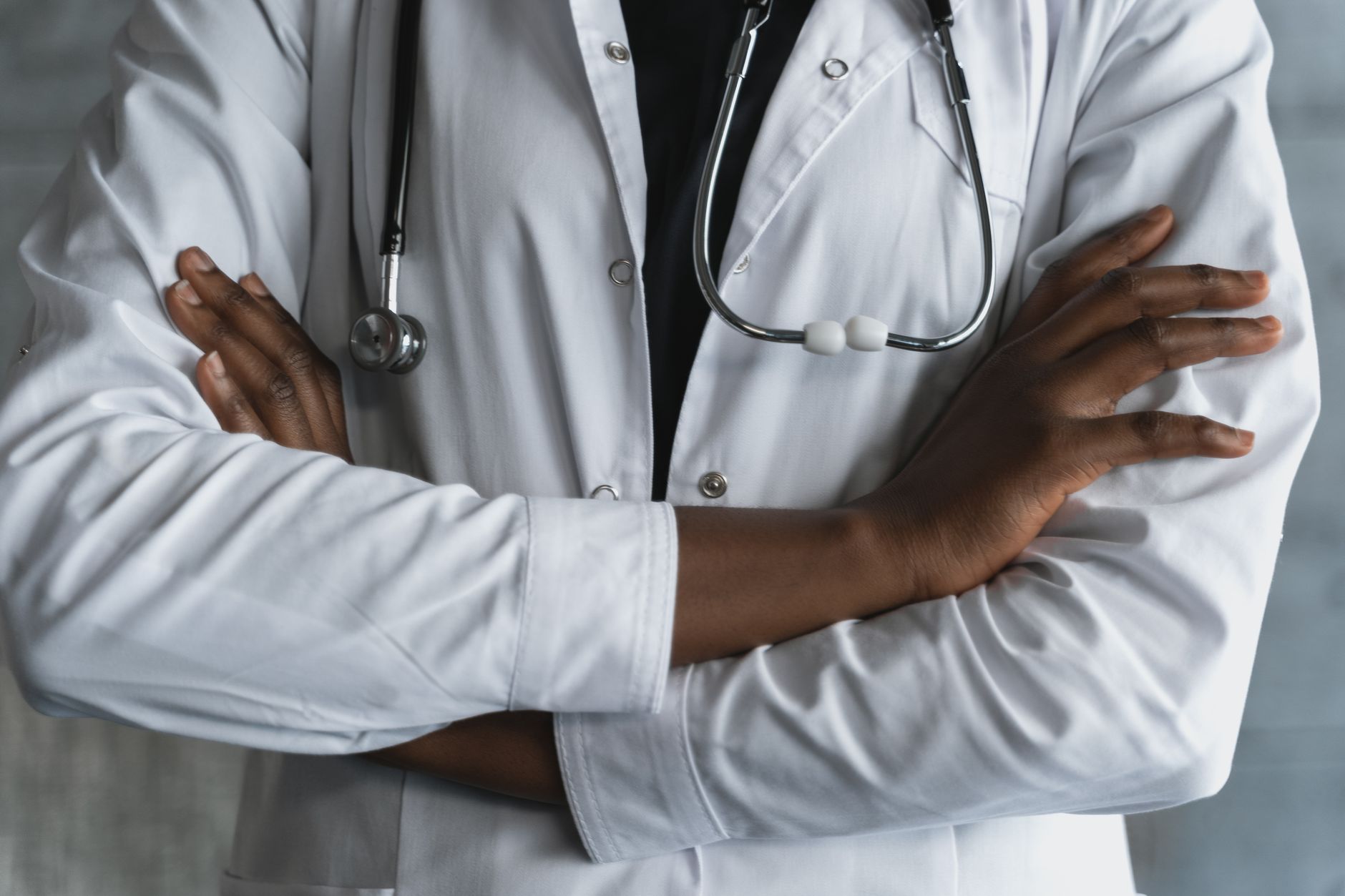 Close-up of a confident doctor in a lab coat standing with crossed arms and stethoscope. — Expert Minimally Invasive Spine Su
