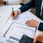 Professionals analyzing financial charts in a corporate setting. — From Childhood Aspirations to Measurable Global Change: Th