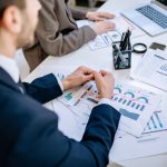 Business team analyzing financial graphs at a meeting table, fostering collaboration in an office environment. — Getting Star