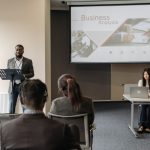 Business seminar with a speaker and audience in a conference room. — GTA 5 Modded Accounts and Gaming Strategy