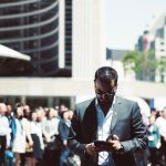 Focused businessman using tablet in a bustling crowd in Toronto's busy urban setting. — Nang Delivery Online | Quick Ordering