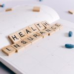 Scrabble tiles spelling 'Health Insurance' on a calendar with pills. — Online Testosterone Therapy Options Through Licensed V