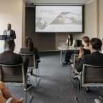 A diverse group of adults attending a presentation in a conference room setting. — Preparing the Next Generation of Public Sa