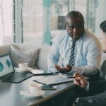 Two business professionals engaged in discussion over laptops and documents. — Reach Maximum Potential with Professional Inst