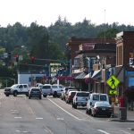 Lively urban street with cars, shops, and pedestrians during daytime. — Reach Out To Influencers and Establish Connections Th