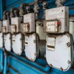 Multiple smart utility meters lined up on a blue industrial wall. — Significance of Financial Info in Our Every day Life