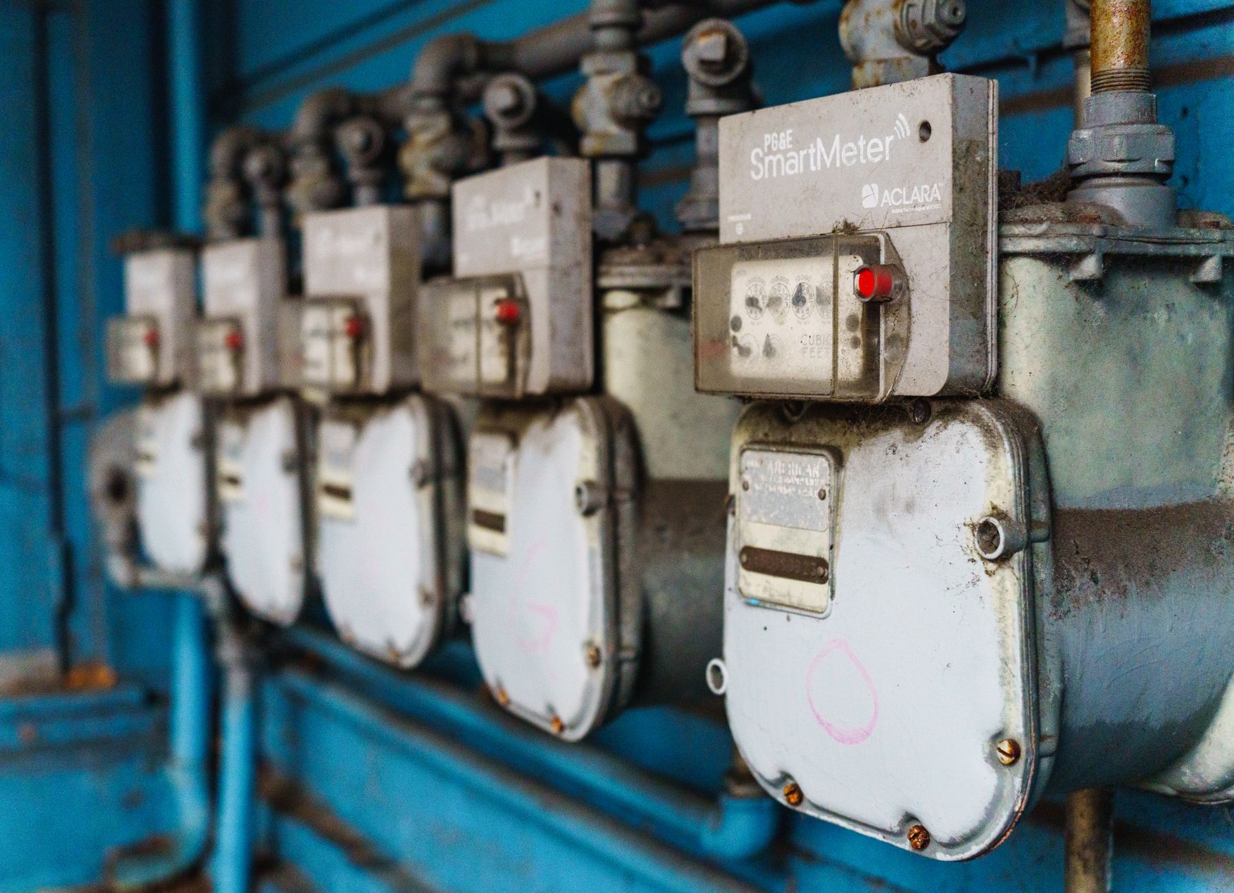 Multiple smart utility meters lined up on a blue industrial wall. — Significance of Financial Info in Our Every day Life