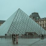 A winter day at the iconic Louvre Museum pyramid in Paris, capturing tourists and the architectural beauty. — Sources for Tre