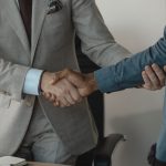 Image of a professional handshake between two businessmen in an office setting. — Sporty and Practical Tommy Hilfiger