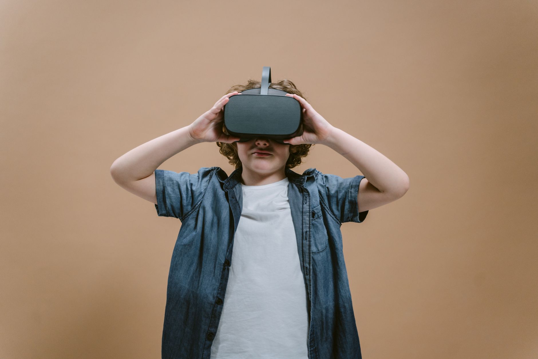Child in studio using VR headset, engaging with modern technology on a plain background. — Variants of Holsters One Can Try