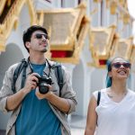 A couple explores a city's ornate architecture, capturing memories with a camera. — When Will The Following Market Crash Mate